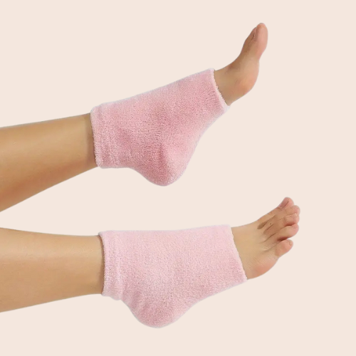 Model wearing pink terry cloth moisturising foot socks against a beige background.
